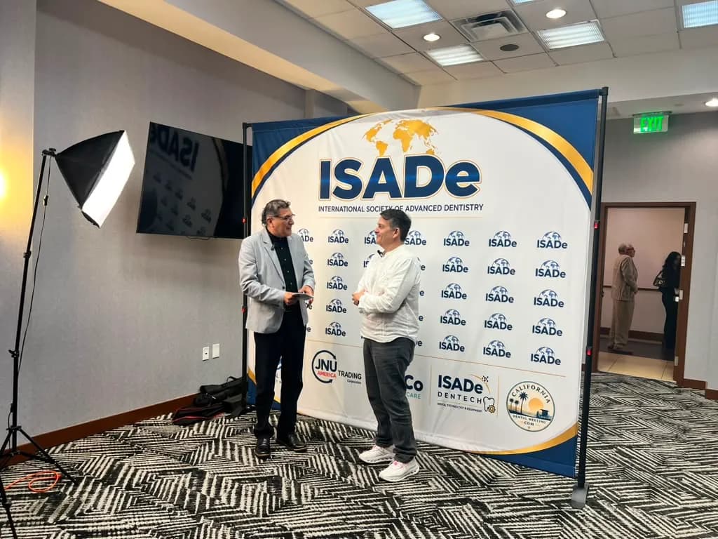 Two colleagues in conversation at the ISADe backdrop.